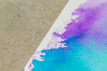 Papel con pintura de acuarela en tonos azules en fondo de cemento