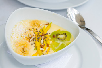 Yogurt con kiwi mango chia en plato de ceramica blanco con manteles blancos