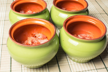 Raw sliced chicken breast fillets in ceramic pot for cooking in the oven.