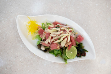 spicy tuna and mix vegetable salad in white plate on table .