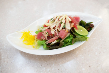 spicy tuna and mix vegetable salad in white plate on table .