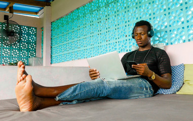 young handsome and cool black African American hipster man with headphones networking relaxed with...