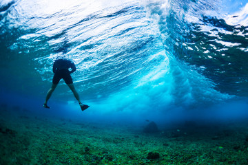 Underwater photographer floats in the wave with big wave breaking in the frame