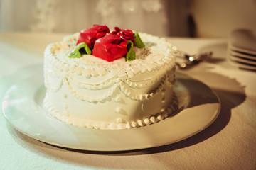 Obraz na płótnie Canvas Verzierte Torte mit roten Rosen vor Tortenanschnitt an Hochzeit
