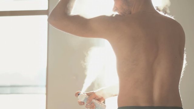 Slow motion footage of man spraying deodorant abundantly in armpit