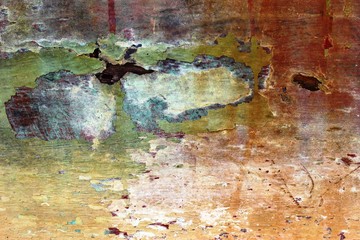 Abstract textured background of an old decaying wooden boat hull with mostly red and orange color peeling paint.