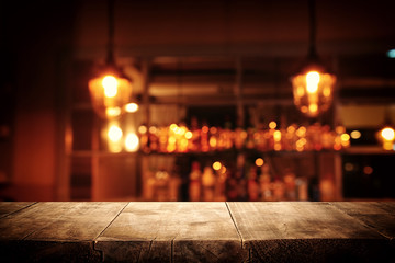 Image of wooden table in front of abstract blurred restaurant lights background