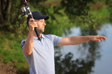 Fisherman throwing bait to river. Man with spinning. Fishing
