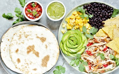 Mexican Buddha bowl with chicken meat fiber, black beans, corn, avocado rose, nachos corn chips. served with avocado sauce (avocado mayonnaise) and tomato salsa (Pico de Gallo) and tortillas