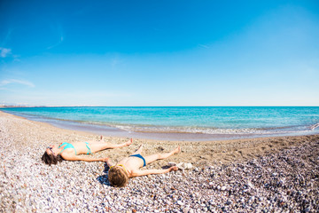 Naklejka na ściany i meble The boy with his mother sunbathe on the beach.
