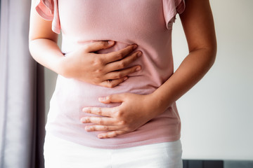 Woman is Having Stomach Ache or Menstrual Period, Close-Up of Young Woman is Suffering From Abdominal Menstruation Pain at Her Resting Room. Healthcare and Medicine Concept