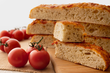 Fototapeta na wymiar Focaccia, Italian Homemade Bread, and Tomatoes Close Up on a Wooden Chopping Board