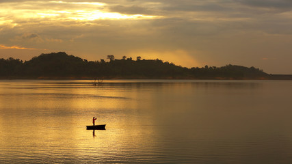 Silhouette of a fishing people on the boat in the middle of the water in the beautiful morning light