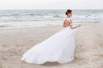 Fototapeta na wymiar Portrait of a beautiful bride on the beach in windy weather
