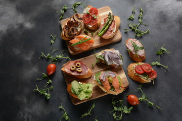 Brushetta or traditional Spanish-tapas. Appetizers with Italian antipasti snacks. Variety of small sandwiches with prosciutto,cherry tomatoes, salmon, cream cheese, cucumber, radish, asparagus