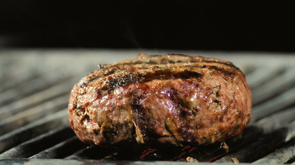 A big fat juicy burger cutlet comes to its readiness on the grill, heat and smoke.