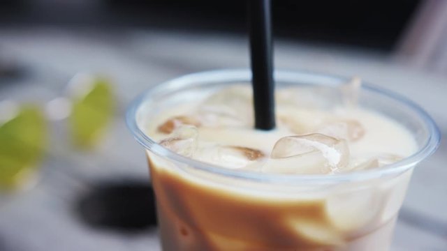 Close-up of delicious coffee drink with ice cubes inside the modern cafe in the city center.