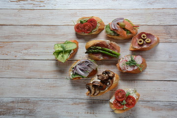 Brushetta or traditional Spanish-tapas. Appetizers with Italian antipasti snacks. Variety of small sandwiches with prosciutto,cherry tomatoes, salmon, cream cheese, cucumber, radish, asparagus