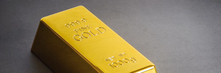 Gold bar ingot bullion on a gray background. Located diagonally.