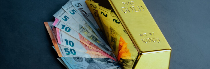 Gold bar ingot bullion against the background of dollar and euro bills.