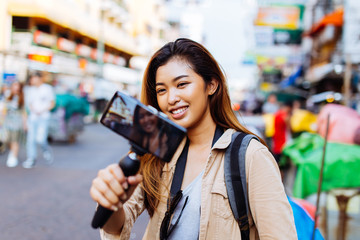 Young Asian female tourist woman holding a gimbal with smartphone and recording videos for blog....