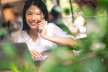 beautiful asian woman happiness working with laptop and smartphone incafe with view from window outside