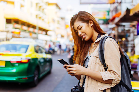 Young Asian female tourist woman using a mobile phone in Bangkok, Thailand. Calling a cab or finding information during traveling concept