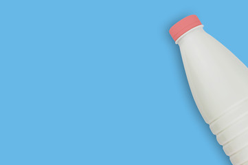 Fresh dairy product in full plastic bottle for milk, kefir or yoghurt with red cap on blue table on...