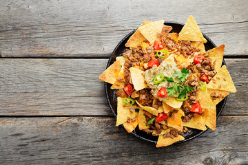 Corn chips nachos with fried minced meat and guacamole on wooden background. - obrazy, fototapety, plakaty