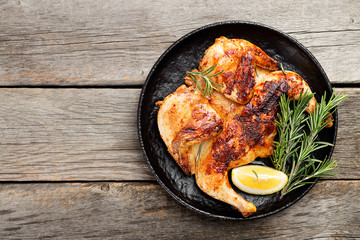 Grilled chicken Tabaka with sauce on  wooden background.