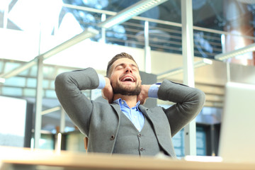 Portrait of a delighted businessman relaxing in his office.