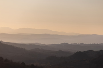 Beautiful view of Tuscany hills at sunset, with mist and warm colors