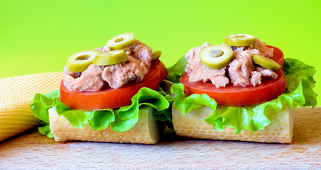 Tuna sandwich on wooden tray. Green background.