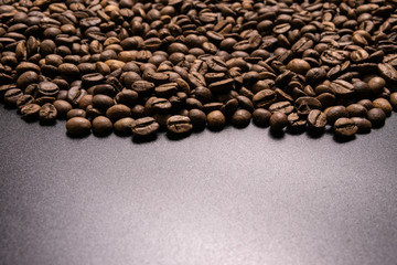 Roasted coffee beans in bulk on a black background. dark cofee roasted grain flavor aroma cafe, natural coffe shop background, top view from above, copy space
