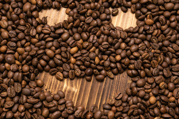 Roasted coffee beans in the form of a smiling face on a wooden background