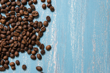 Roasted coffee beans in bulk on a blue wooden background. dark cofee roasted grain flavor aroma cafe, natural coffe shop background, top view from above, copy space