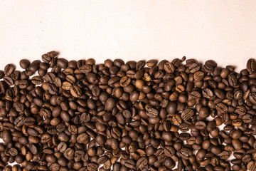 Roasted coffee beans in bulk on a light pink background. dark cofee roasted grain flavor aroma cafe, natural coffe shop background, top view from above, copy space