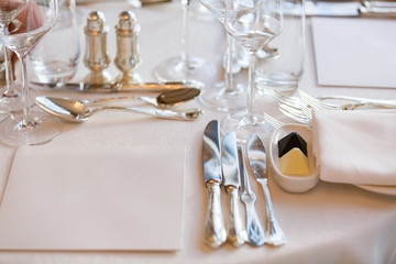 Wooden table served with plates, forks, spoons, glasses, napkins in the restaurant