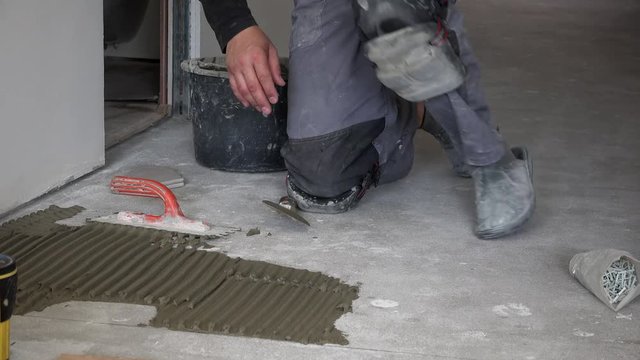 man apply glue cement on floor and lay hexagon tile