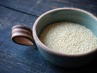 white sesame seeds in a bowl on a blue wooden background