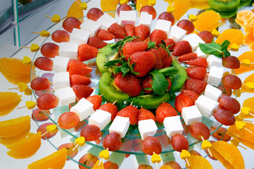 fruit dessert with cheese skewers laid out on a plate in a circle