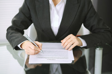 Business woman hands with pen over document of contract at glass table. Agreement signing concept