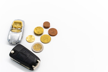 coins with an car and a car key on a white background with copy space