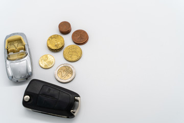 coins with an car and a car key on a white background with copy space