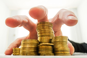 A man's hand is hanging over gold coins and wants to pick them up. Business concept