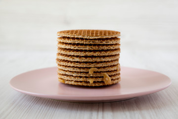 Stack of sweet Dutch stroopwafels with honey-caramel filling on pink plate, side view. Close up.