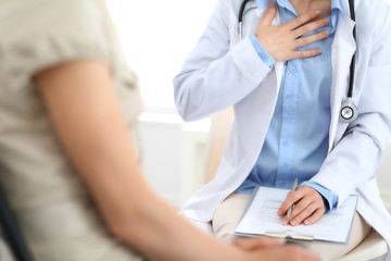 Doctor and patient talking. Physician at work in hospital while writing up medication history records form on clipboard near sitting woman. Healthcare and medicine concepts