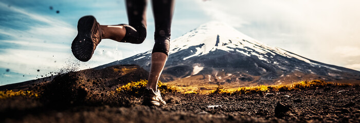 Legs of the woman running on the trail with volcano on the background - 260003647