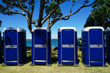 A row of blue toilet cubicles at an outdoor event.