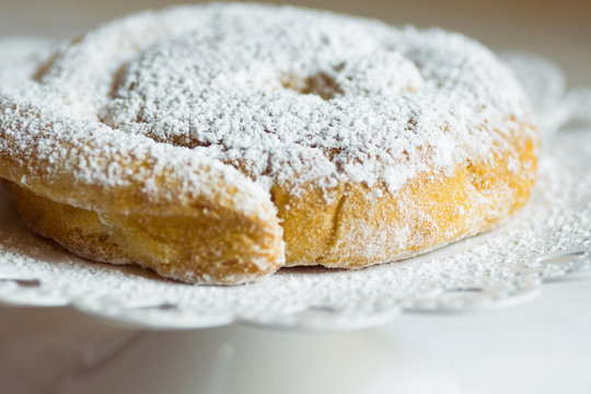 Fresh home baked traditional Spanish and Philippine coiled sweet bread ensaimada sprinkled with icing sugar on cake stand. Rustic style. Local cuisine specialty